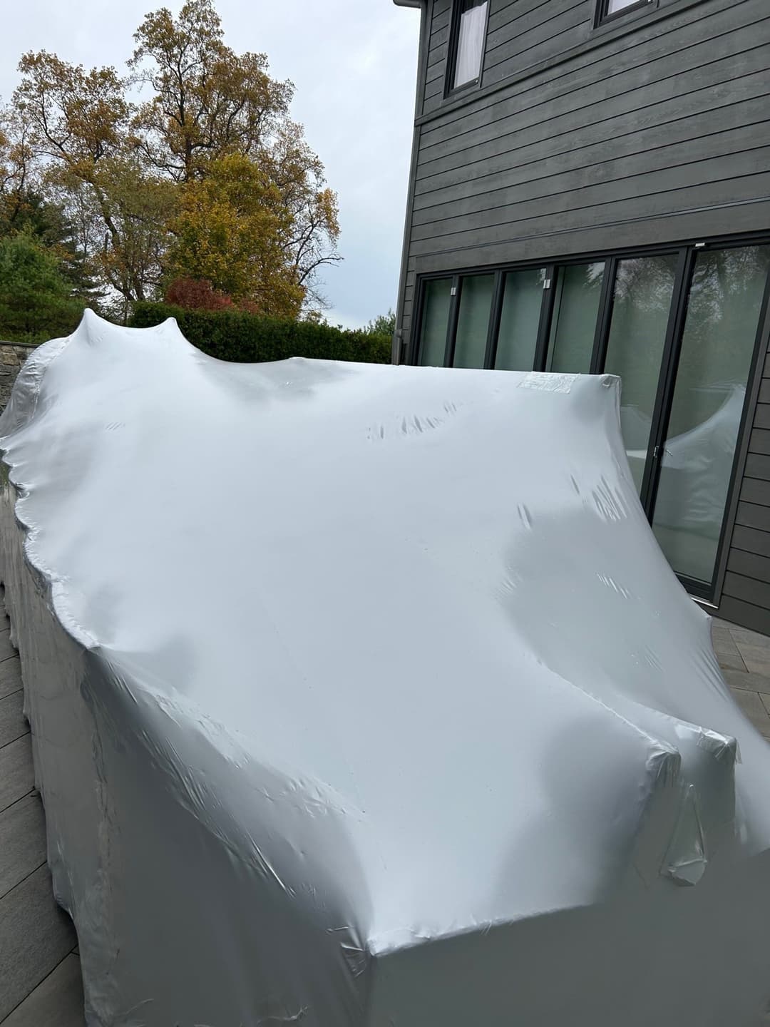 Covered outdoor furniture with protective tarp in a residential backyard setting.