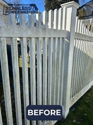 Dirty white picket fence before power washing, showcasing stains and mildew.