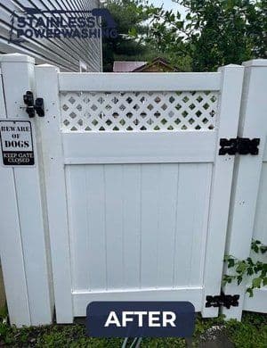 Clean white vinyl gate after power washing, with a "Beware of Dogs" sign visible.