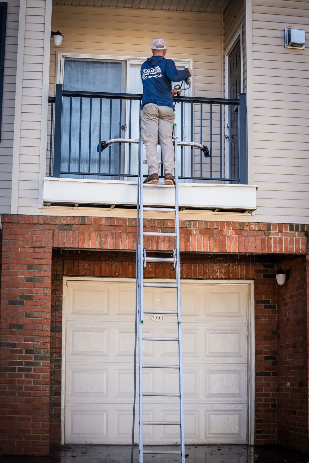 Man using a ladder to work on a balcony of a residential building.