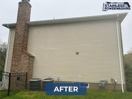 Cleaned vinyl siding and chimney on a house exterior after power washing.