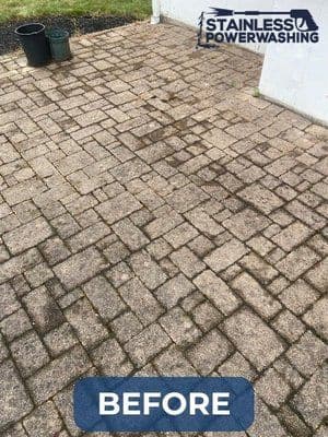 Before image of a dirty brick patio showing stains and grime, showcasing power washing service.